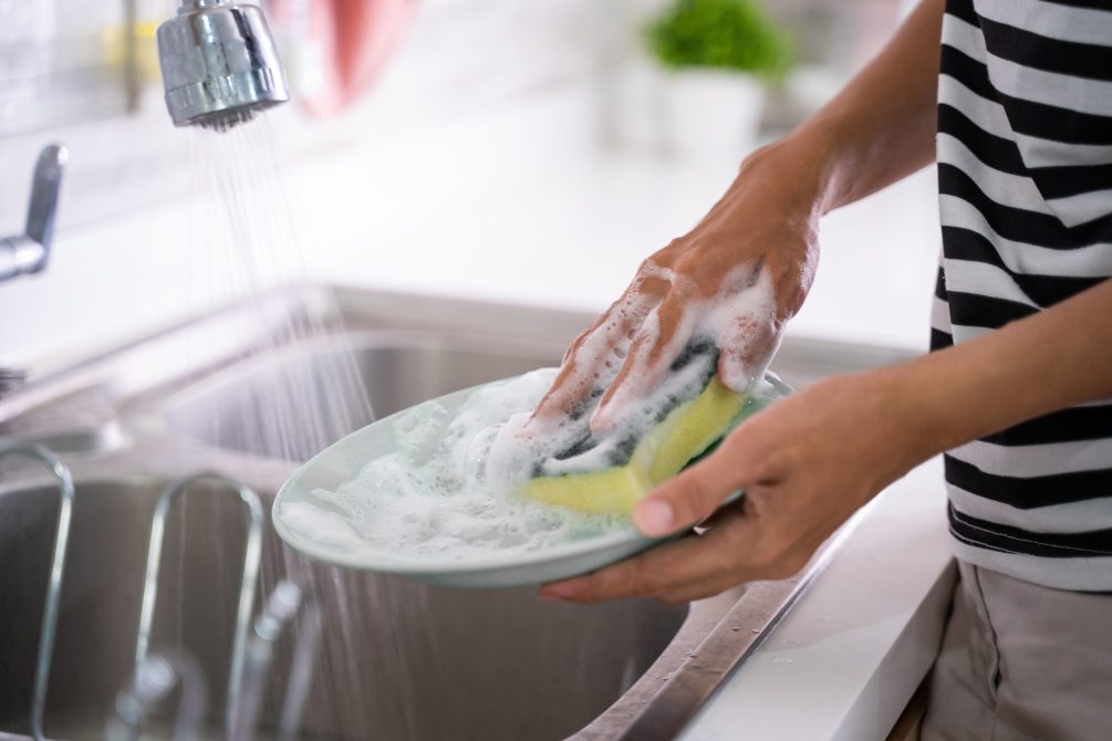 female hand gesture cleaning plate using sponge